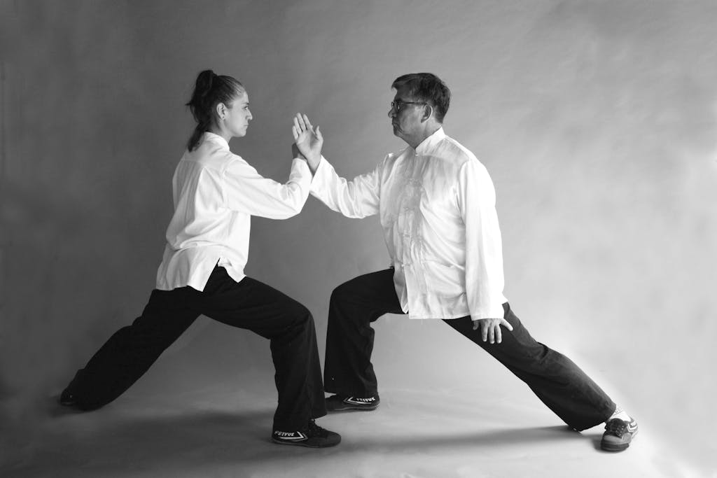 Two people practicing martial arts in dynamic poses wearing traditional clothing.