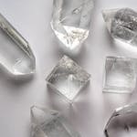 Detailed close-up of various quartz crystals arranged on a white surface.